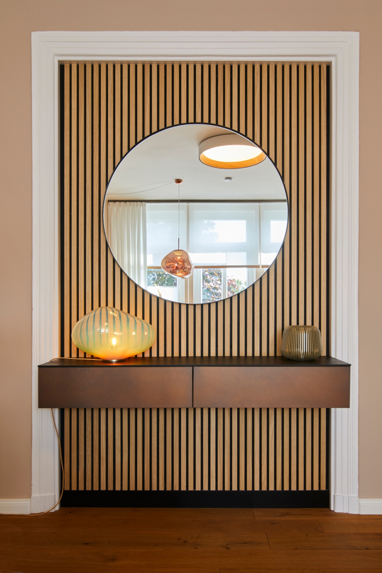Eingangsbereich mit rundem Spiegel und Holzlamellenwand